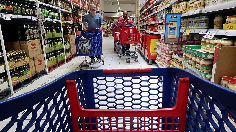 Varias personas empujan un carrito de la compra en un supermercado Carrefour