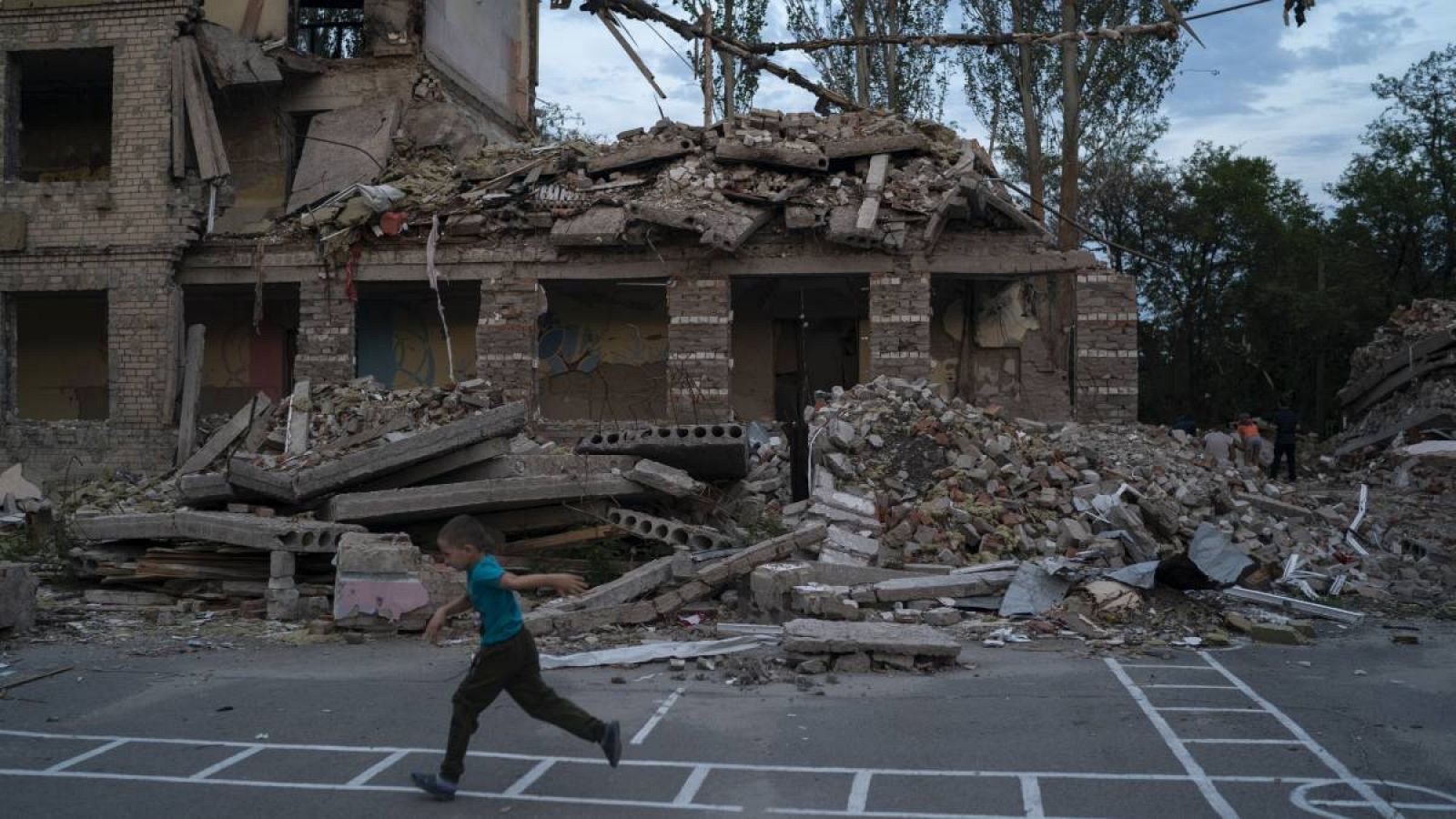 Oleksii Makarov, de 6 años, pasa corriendo frente al edificio donde se encontraba su salón de clases mientras juega en el patio de la destruida Escuela Número 23 después de un ataque ruso que ocurrió en la segunda quincena de julio, en Kramatorsk, Uc