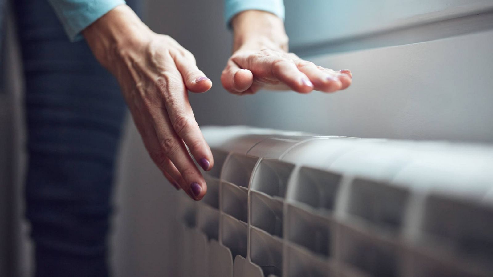 Una persona calienta sus manos con un radiador