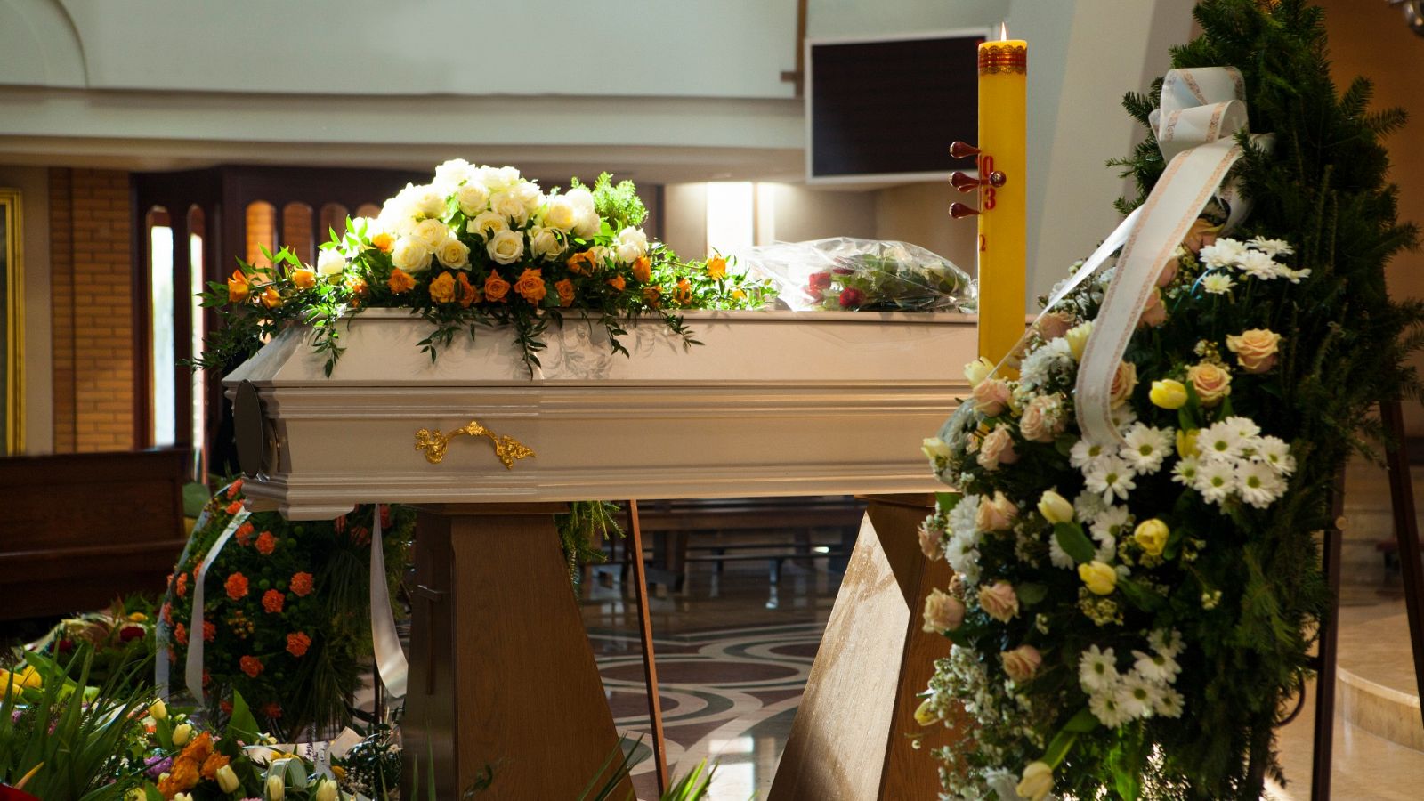 Un ataúd rodeado de flores durante un velatorio