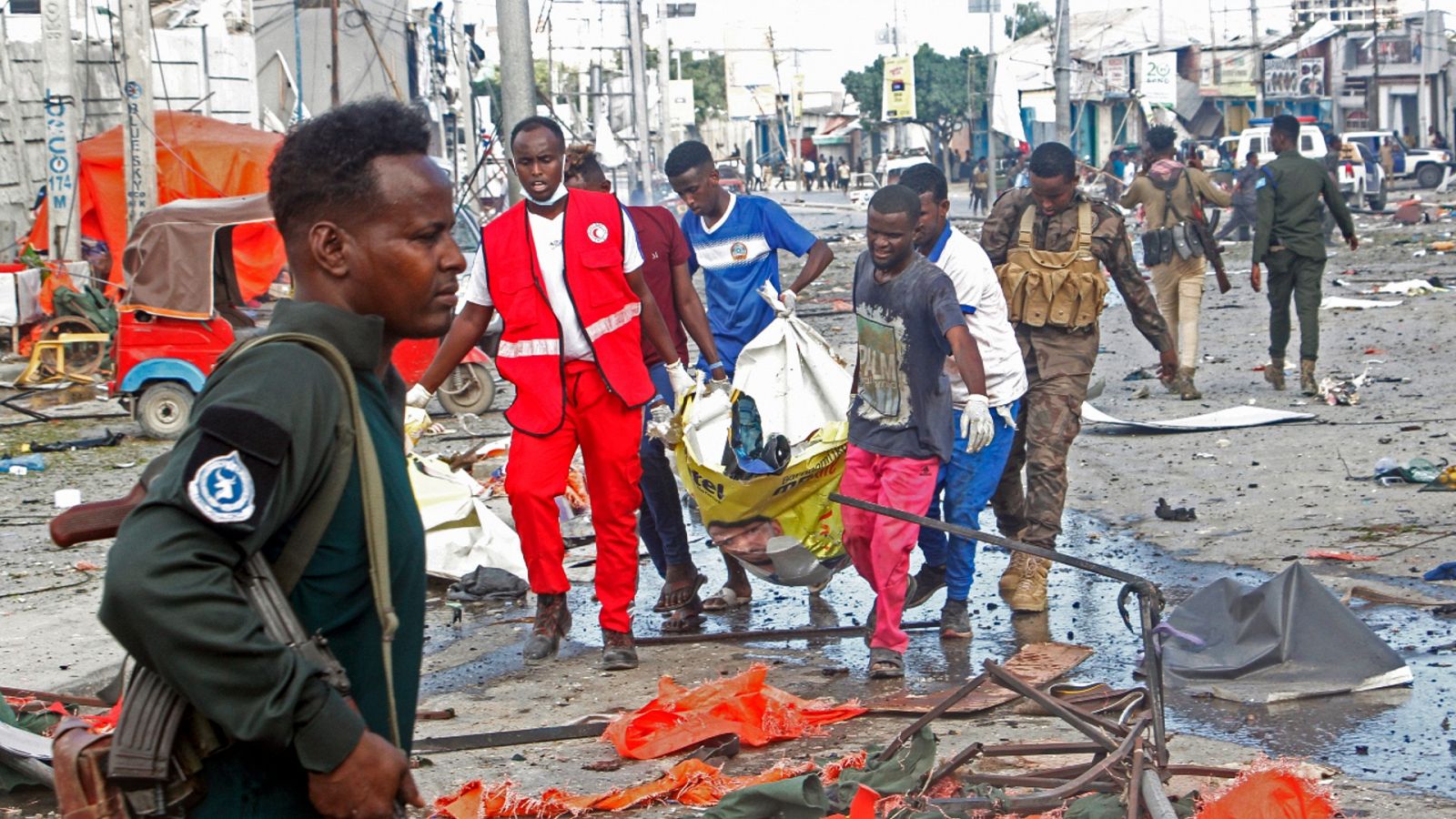 Varias personas retirando el cuerpo de una víctima tras un ataque con dos coches bomba en Mogadiscio, Somalia.