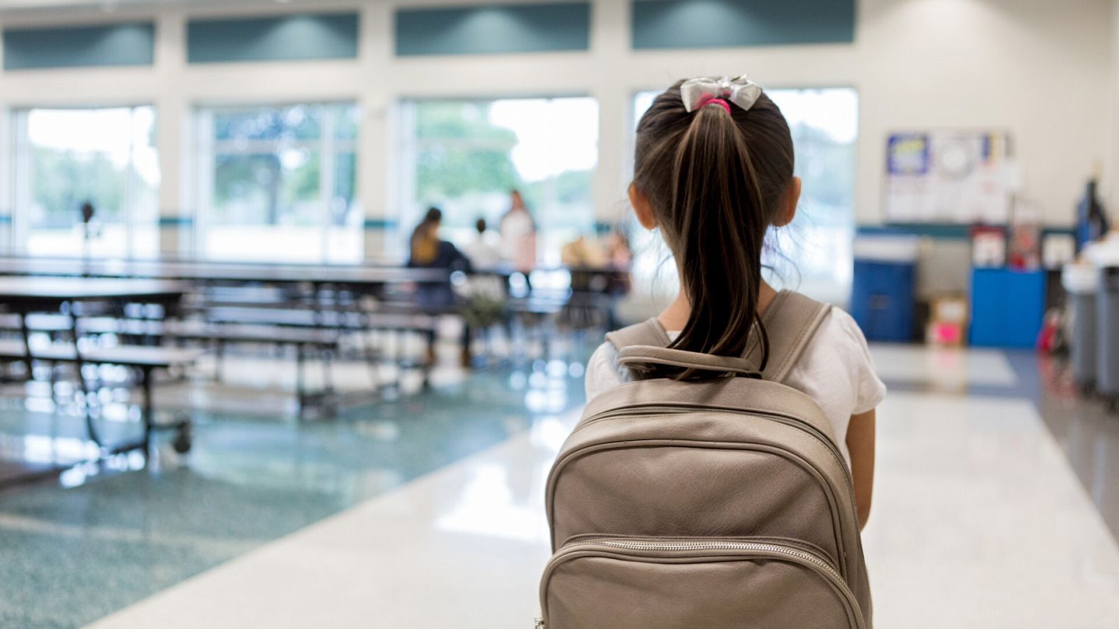 Una niña camina por un colegio con una mochila