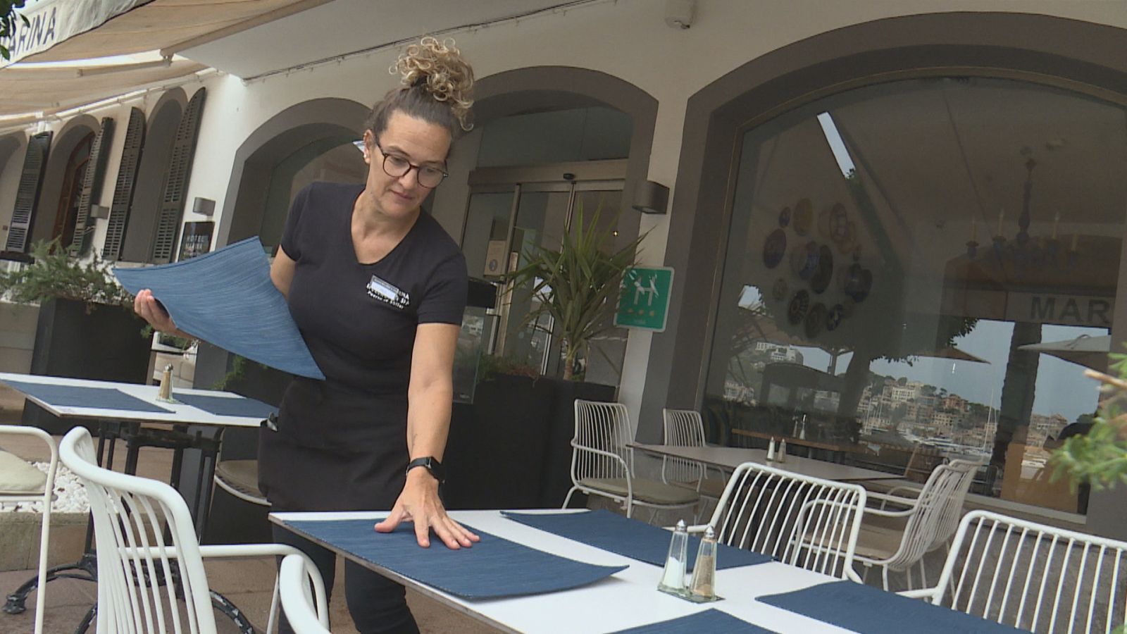 Una treballadora preparant una taula a un restaurant del Port de Sóller