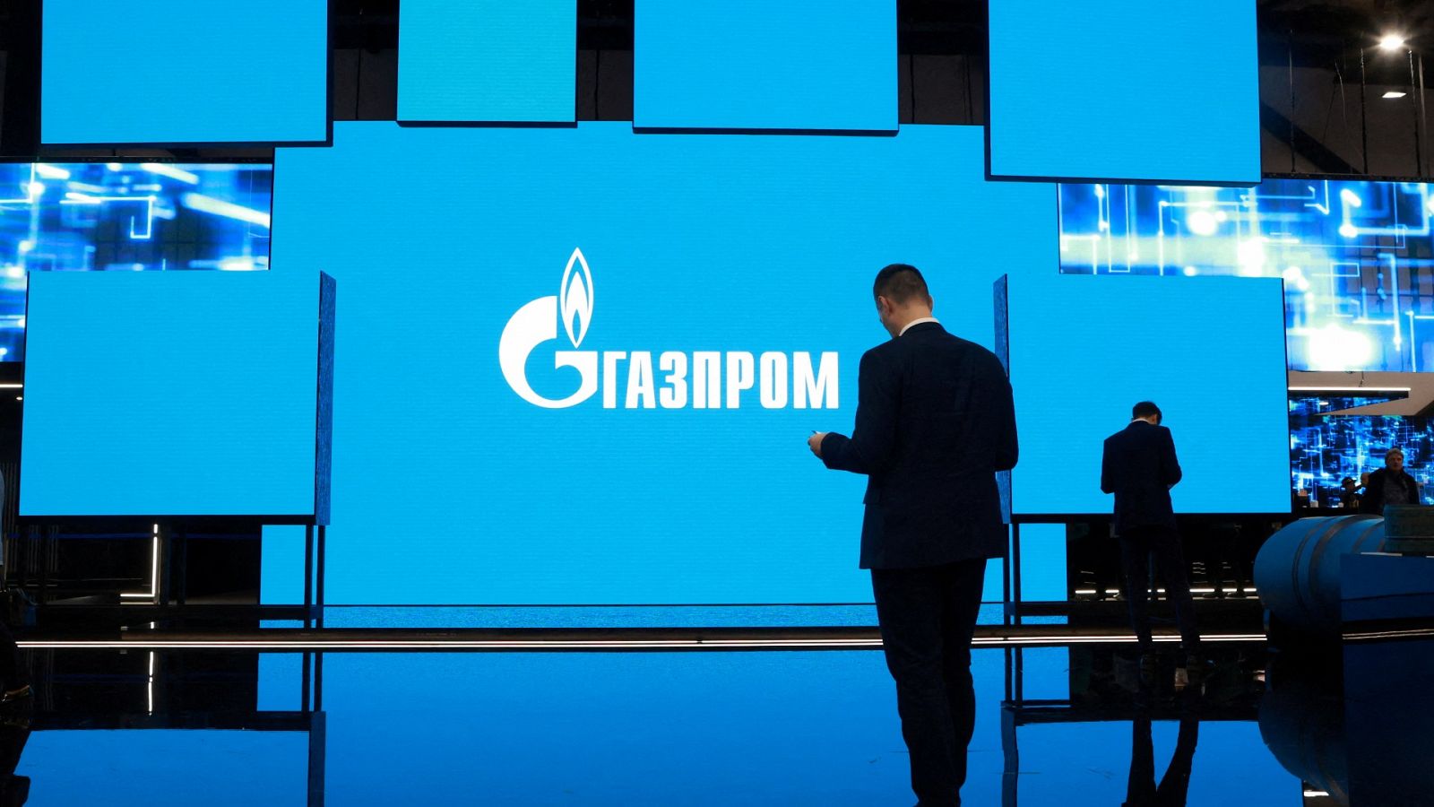 Una persona pasa por delante de una pantalla con el logo de Gazprom en San Petersburgo, Rusia