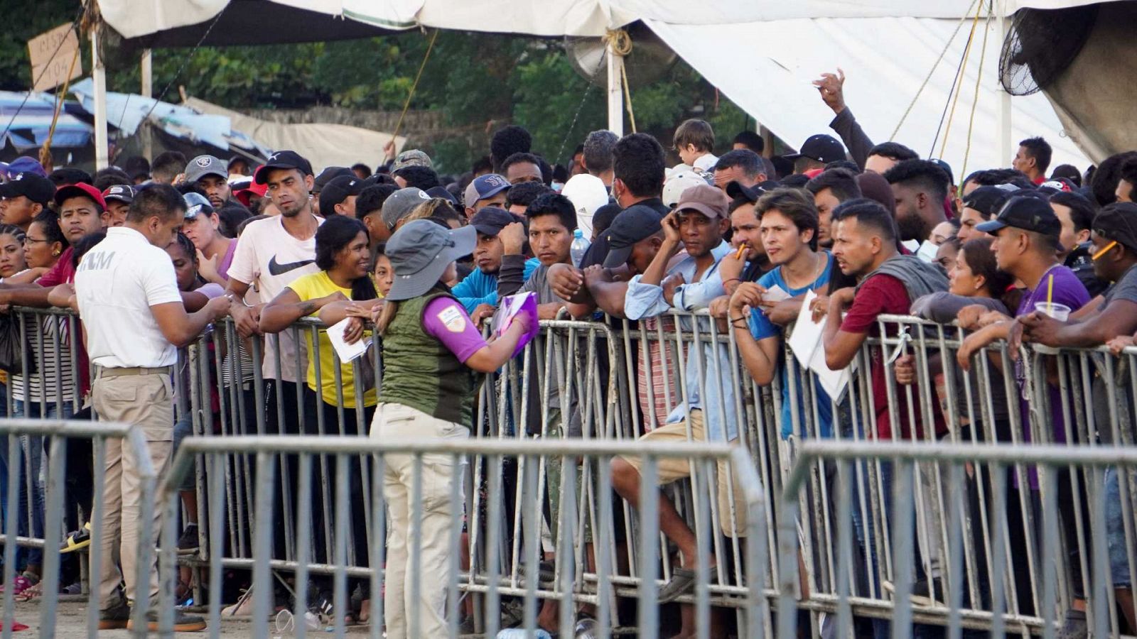 Miembros del Instituto Nacional de Migración hablan con migrantes en un campamento de México.