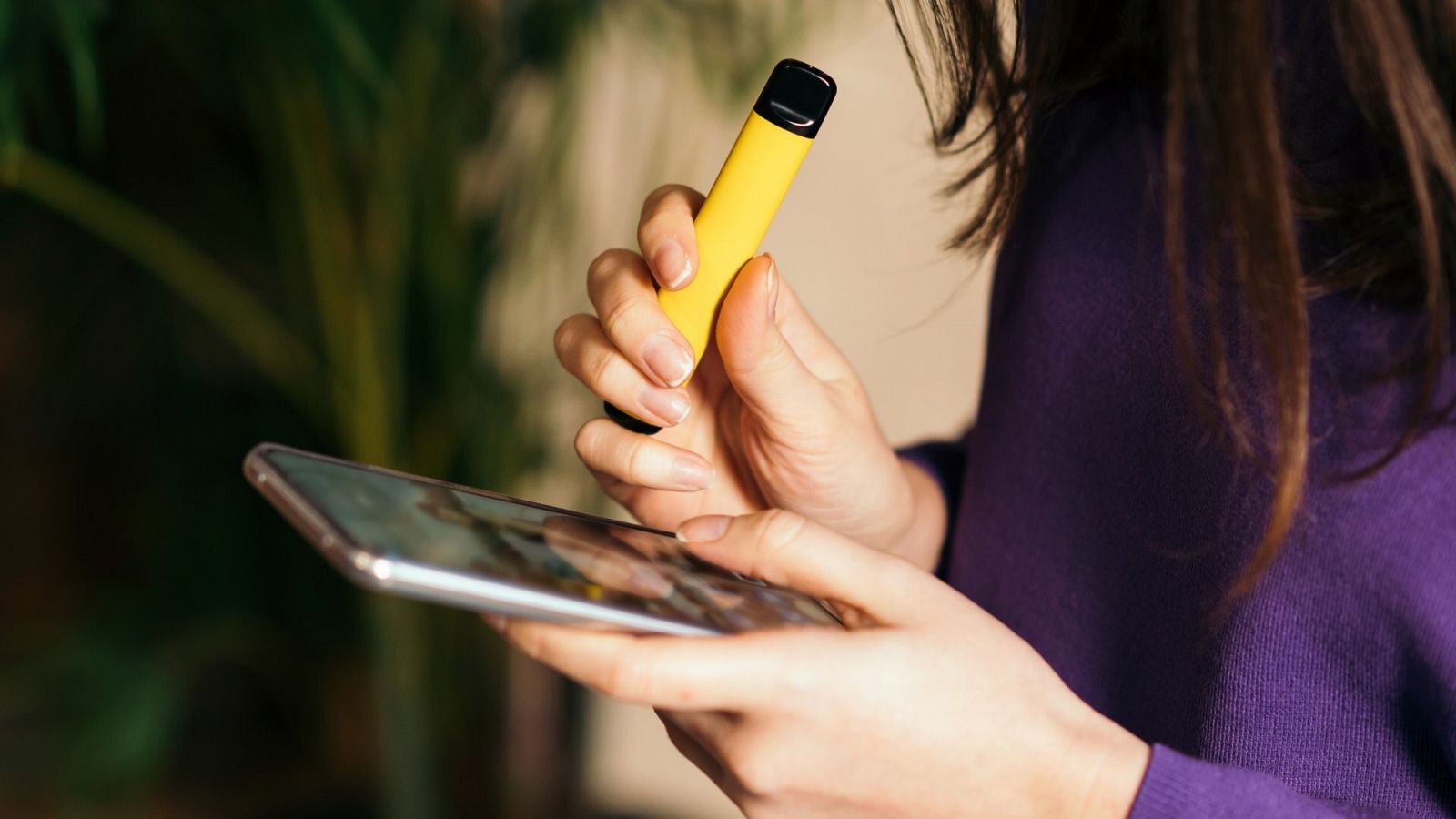 Una mujer utiliza un cigarro electrónico con un envase de color amarillo