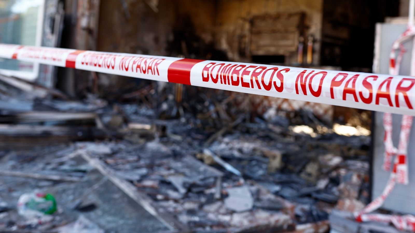 Imagen de archivo de una cinta de prohibido el paso de los bomberos. De fondo se ve un edificio afectado por unincendio.