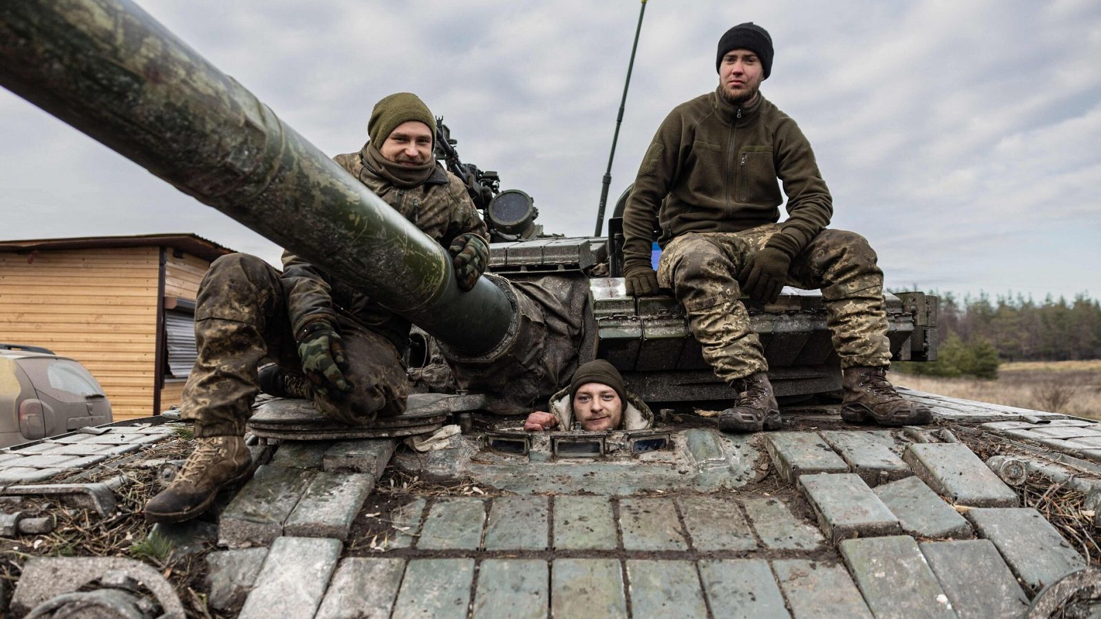 Tres soldados ucranianos encima de un tanque en el campo de batalla