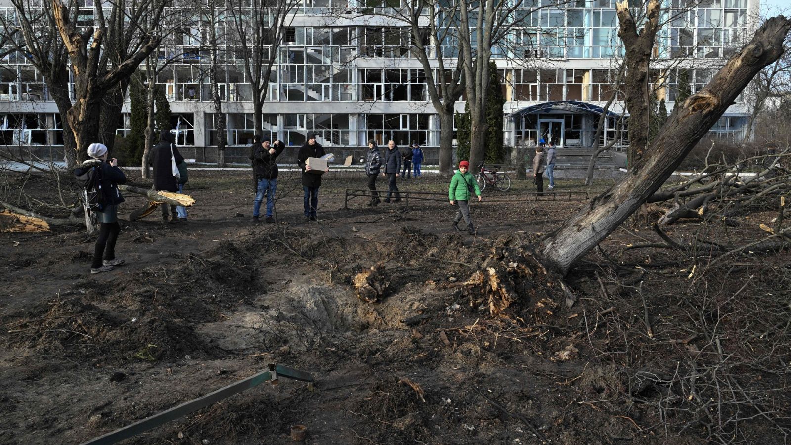 Transeúntes miran un cráter junto a un edificio en Kiev, Ucrania.