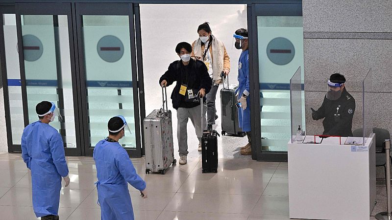 Trabajadores sanitarios guían a los viajeros procedentes de China en un aeropuerto