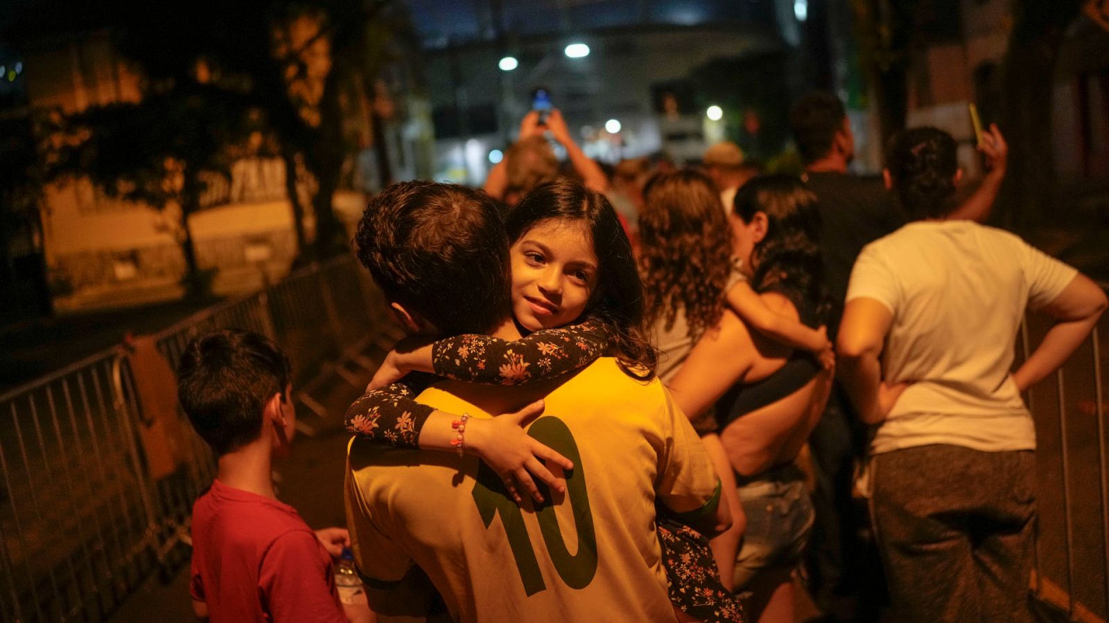 Una niña en brazos de un hombre con una camiseta con el dorsal 10 en la cola para la capilla ardiente de Pelé