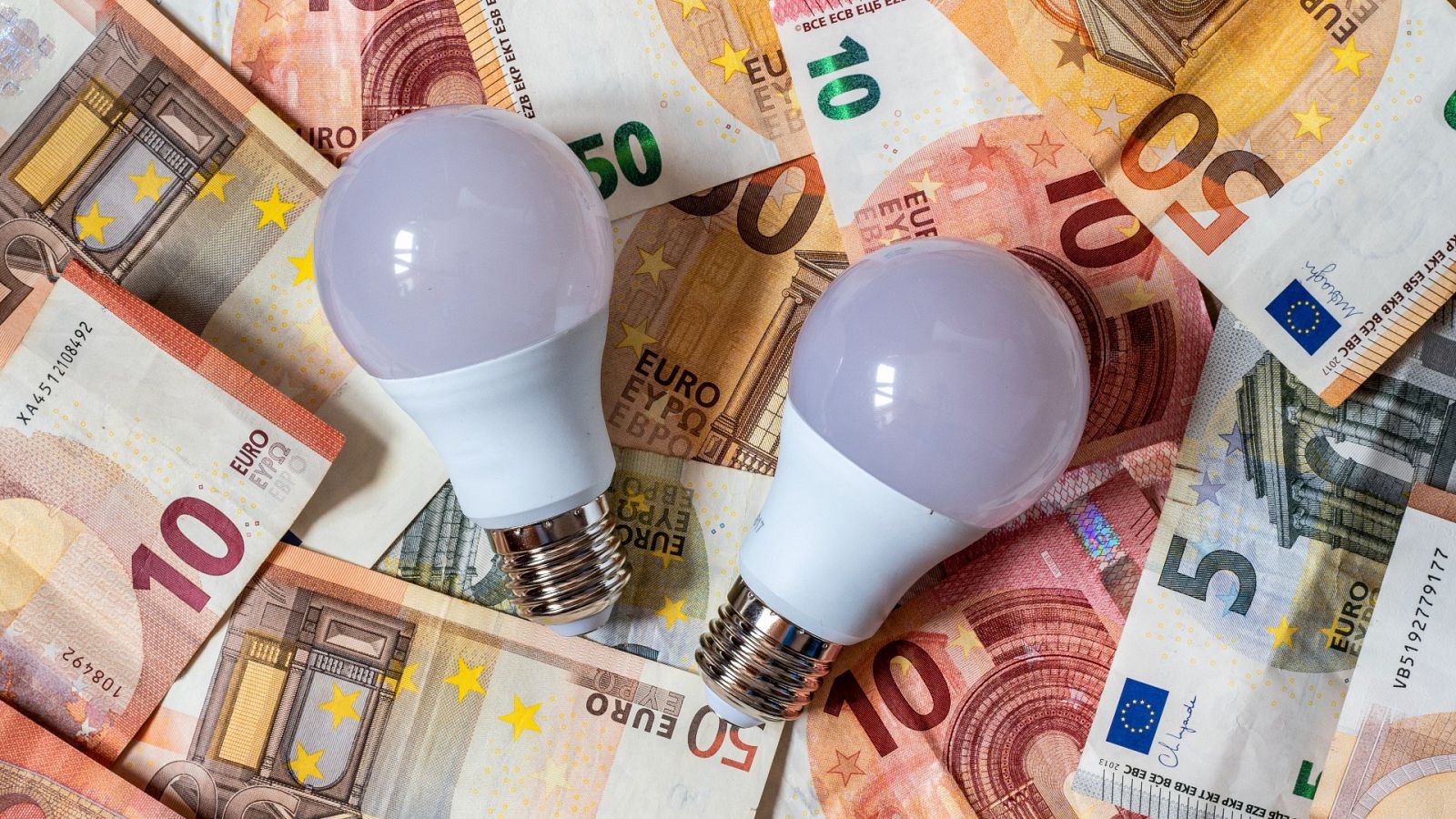 Dos bombillas de bajo consumo sobre varios billetes de euro