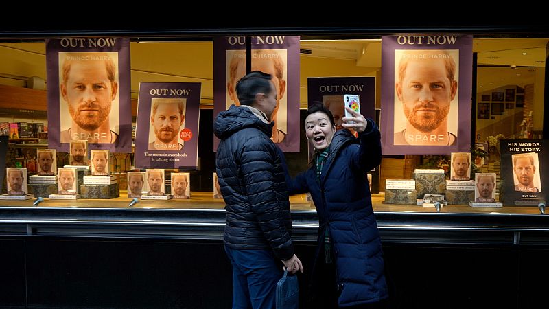 Una pareja se hace un 'selfie' en un escaparate repleto de ejemplares de 'Spare', en Londres