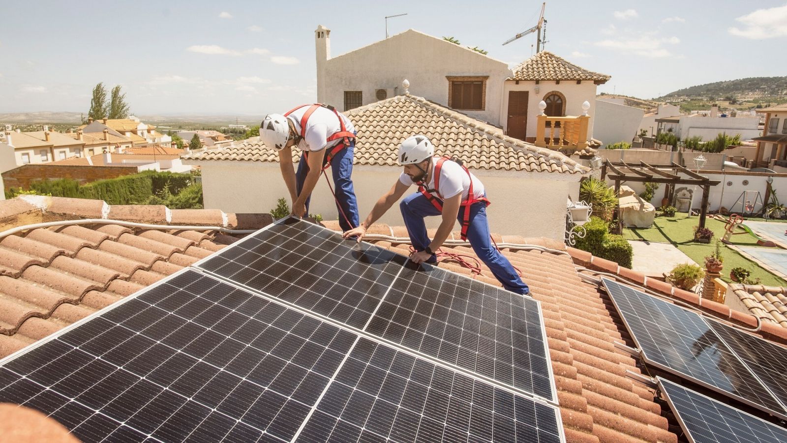 Dos trabajadores instalan placas solares en una vivienda