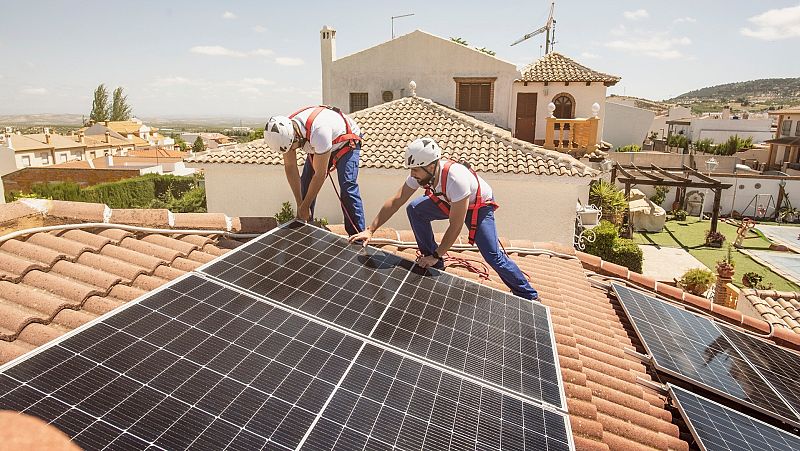 Dos trabajadores instalan placas solares en una vivienda