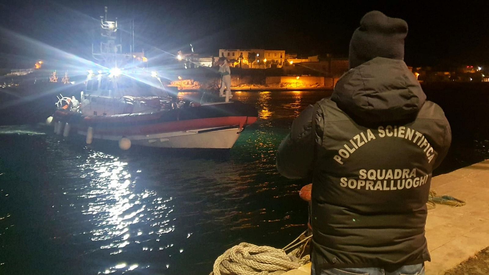 Imagen de policías italianos esperando en el muelle la embarcación con los cuerpos de ocho migrantes en Lampedusa