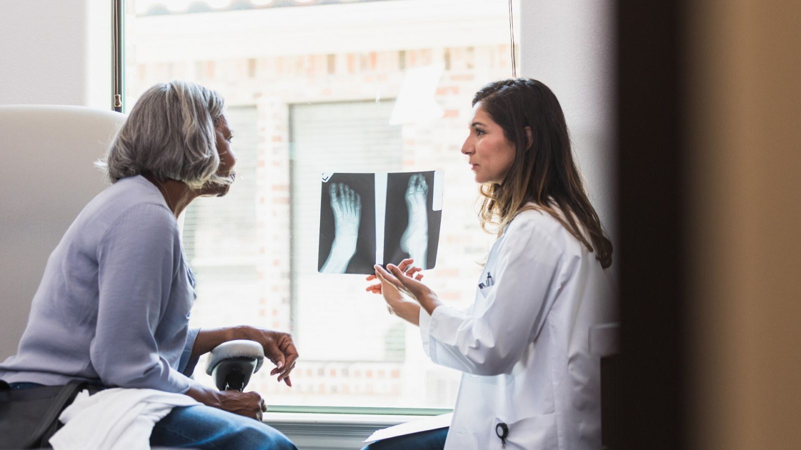 Doctora y paciente observan la radiografía de un pie