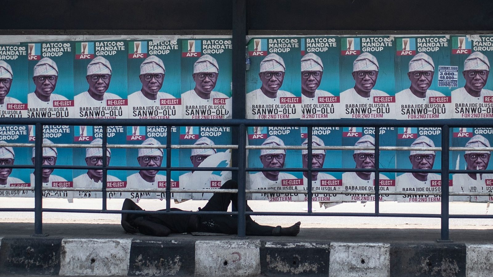 Un hombre duerme en la calle bajo carteles electorales mientras la gente espera los resultados de las elecciones presidenciales, en Lagos, Nigeria