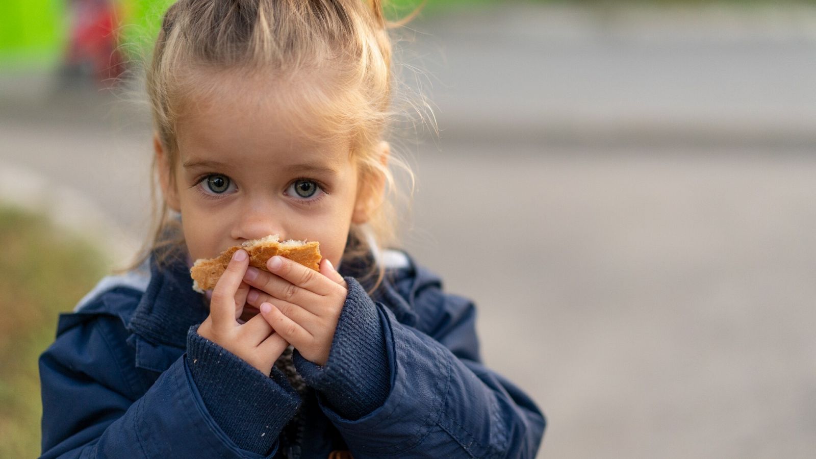 El coste de la pobreza infantil en España: un niña come un trozo de pan