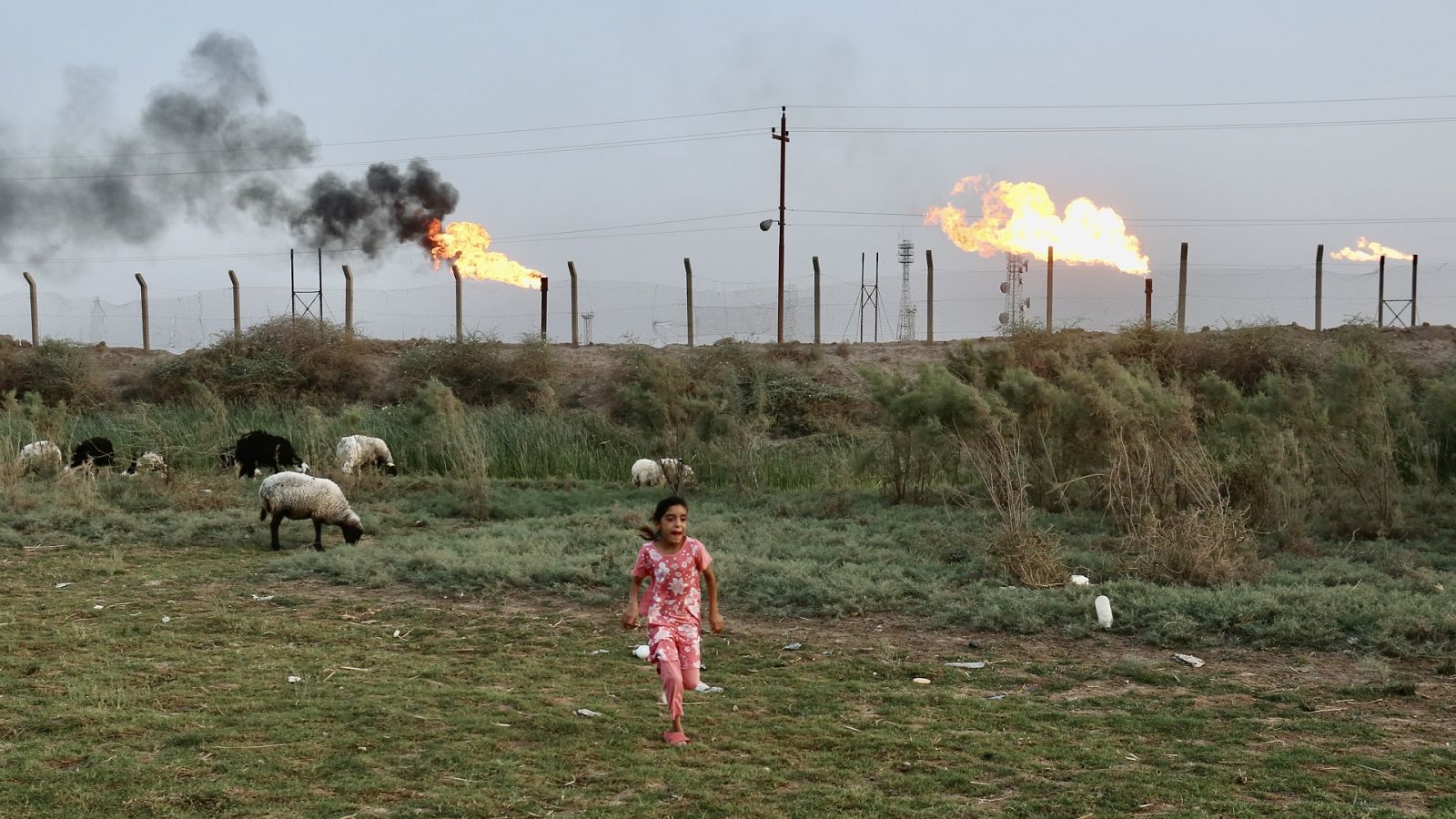 Niña corriendo delante del campo petrolífero Nahran Omar