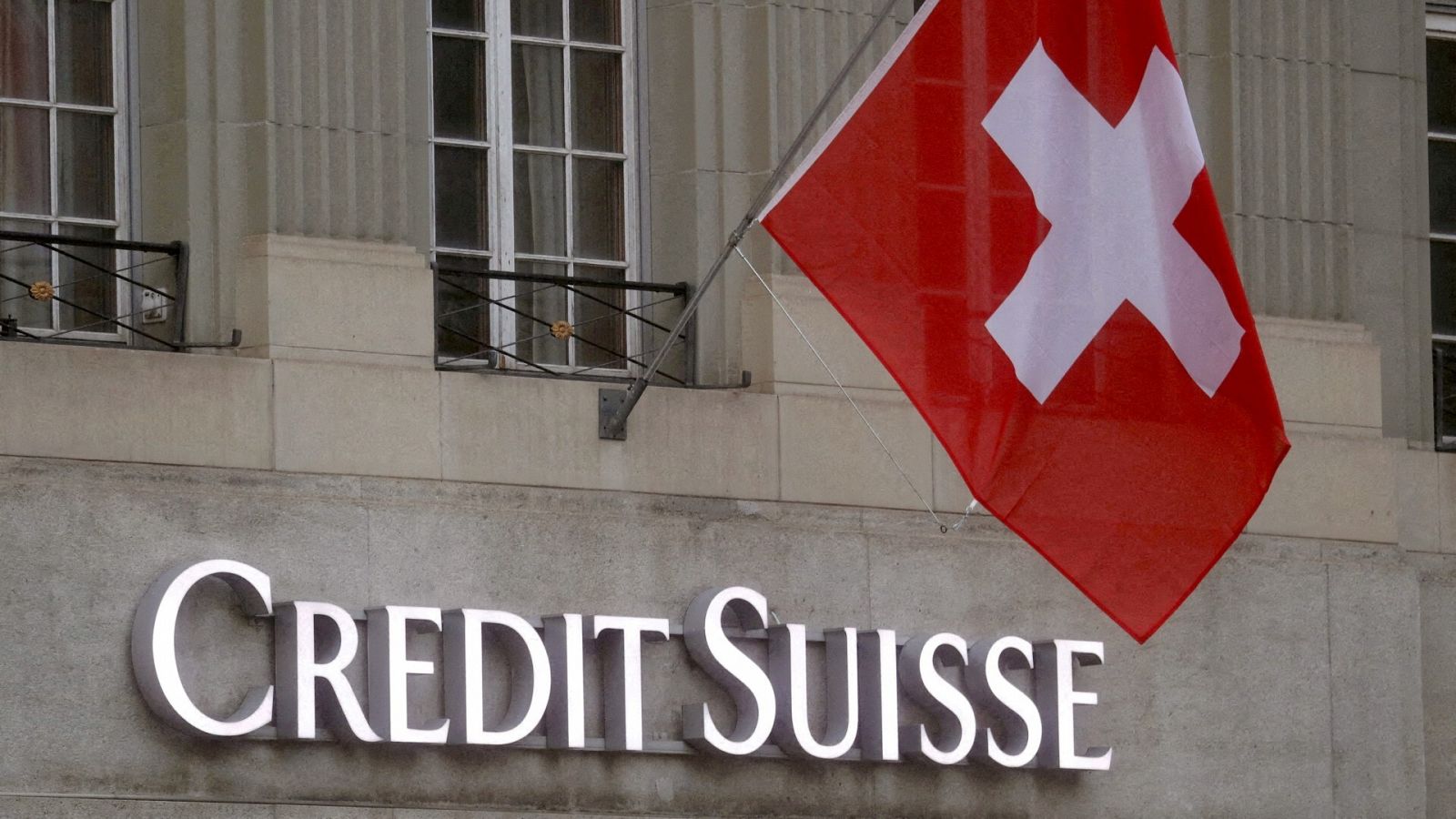 La bandera suiza ondea sobre el logotipo del Credit Suisse frente a una sucursal en Berna