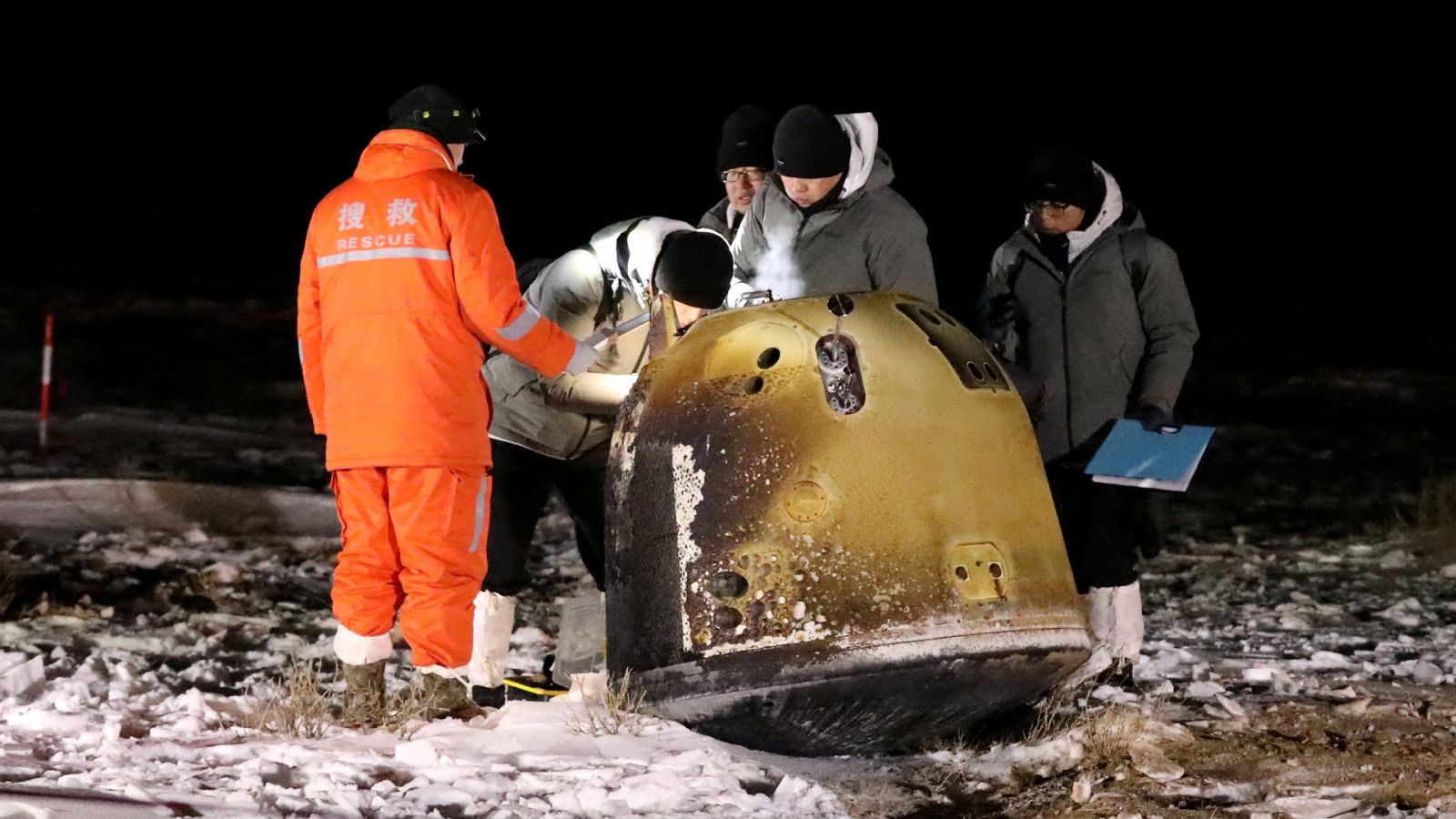 Científicos trabajan junto a la cápsula de retorno de la misión Chang'e-5