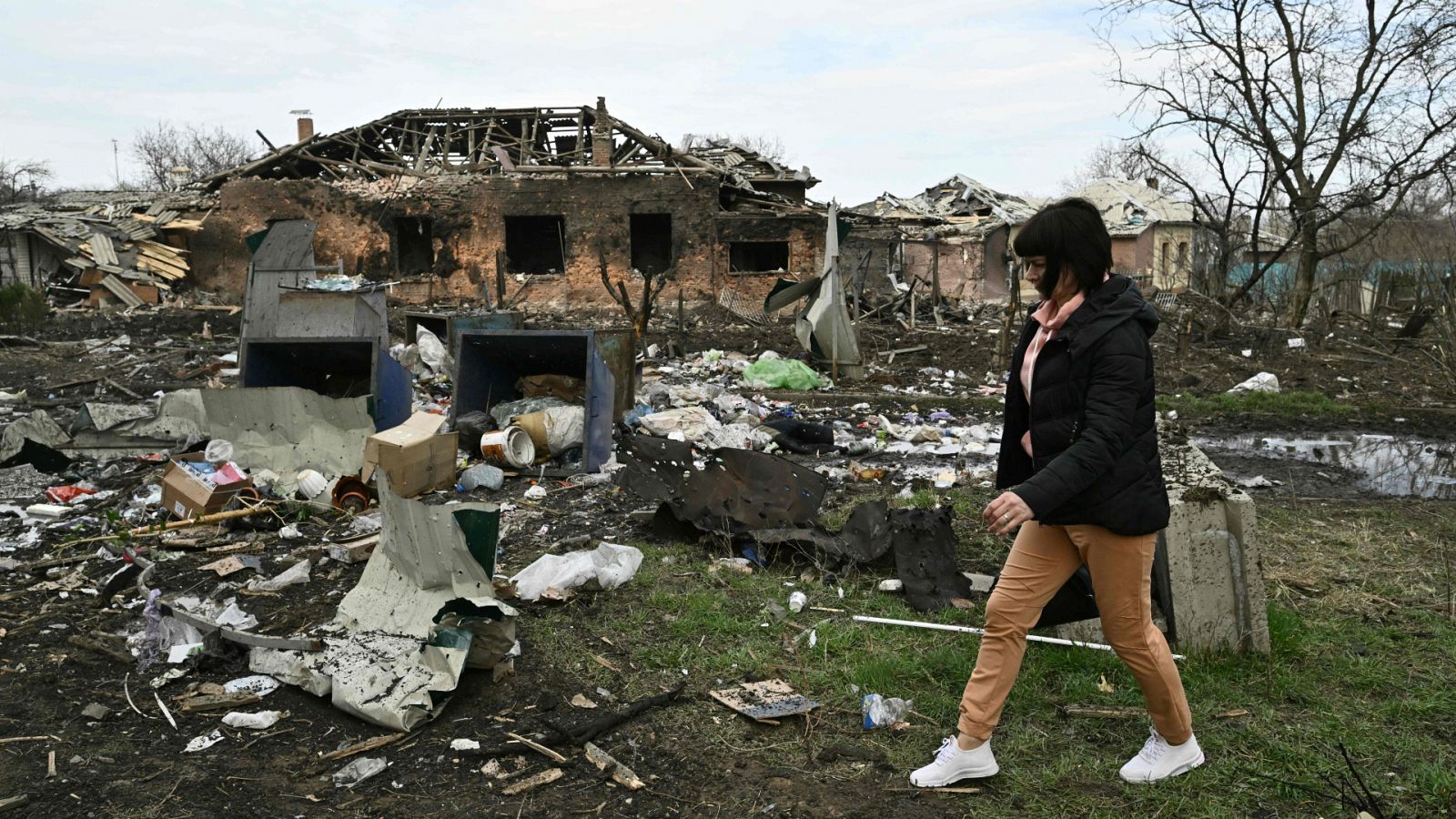 Una mujer camina junto a una casa dañada en un bombardeo ruso en la ciudad de Kostyantynivka