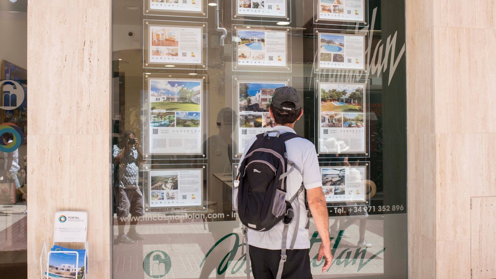 En la imagen, un hombre observa carteles de viviendas en venta y alquiler en Menorca
