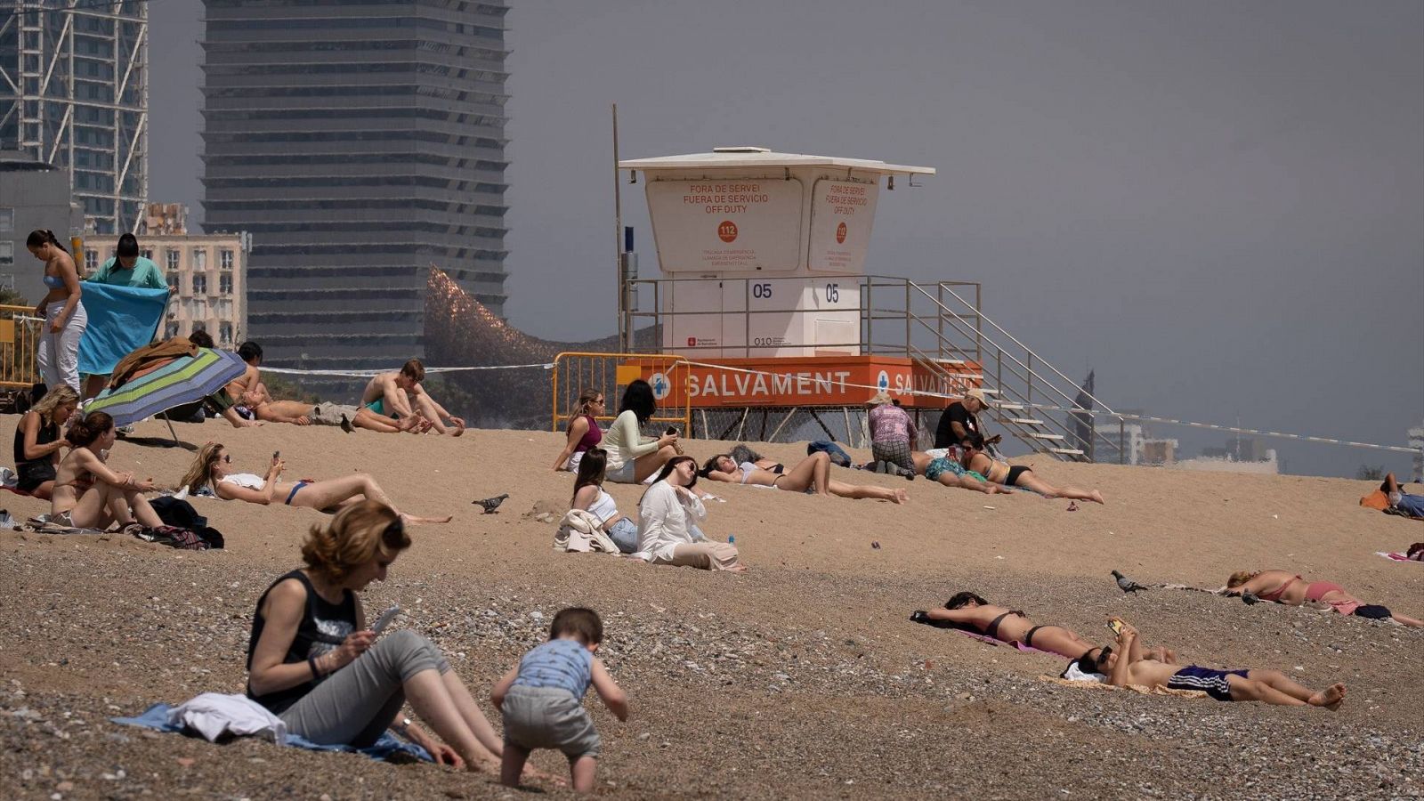 El tiempo hoy: varias personas toman el sol en la playa de la Barceloneta, en Cataluña