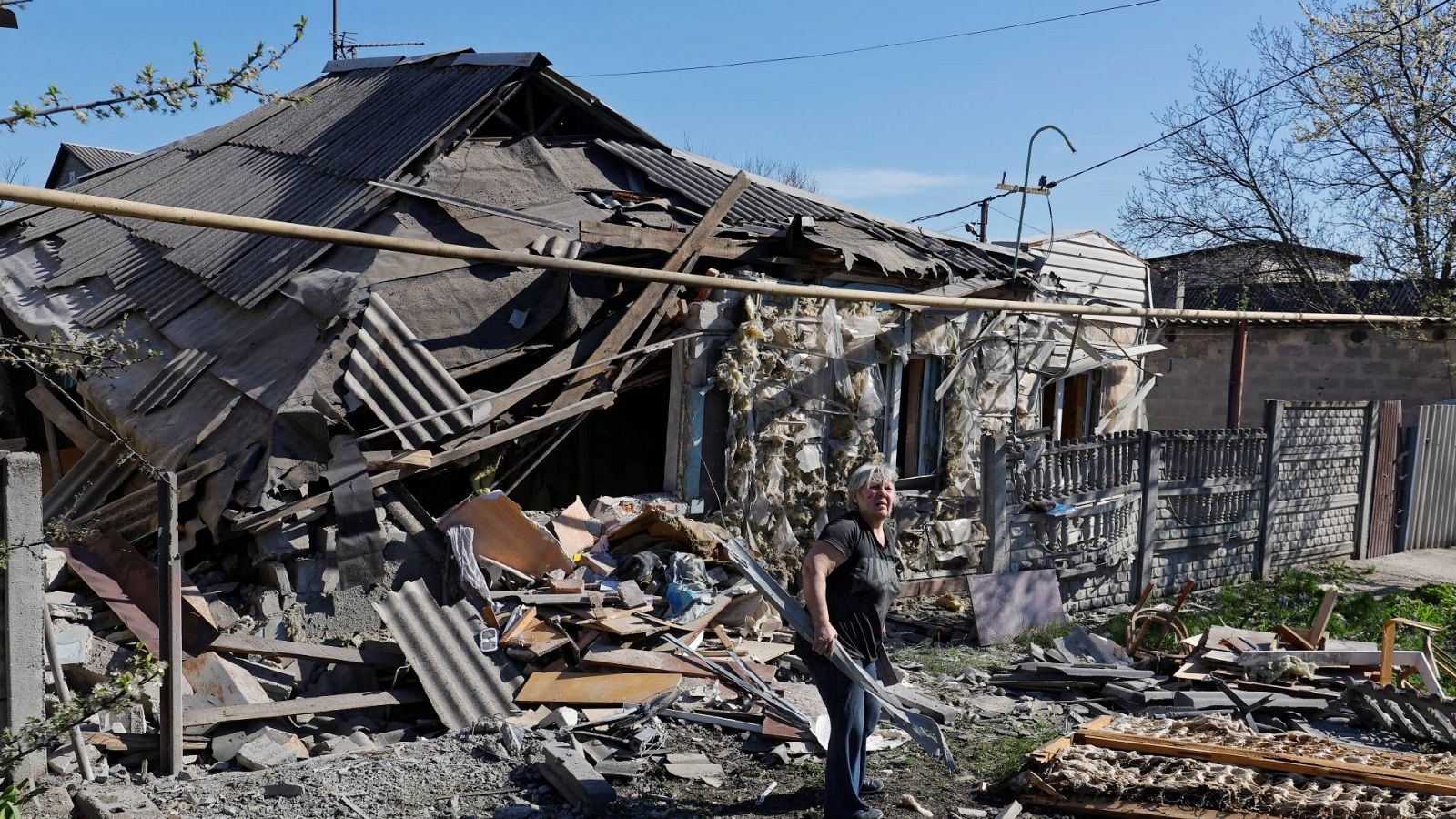 Una residente de Donetsk limpiando los escombros de su casa destruida tras un bombardeo.