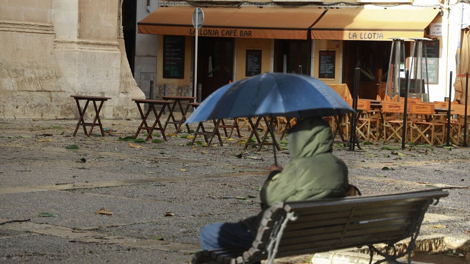 Un hombre con paraguas delante de un bar en Palma de Mallorca