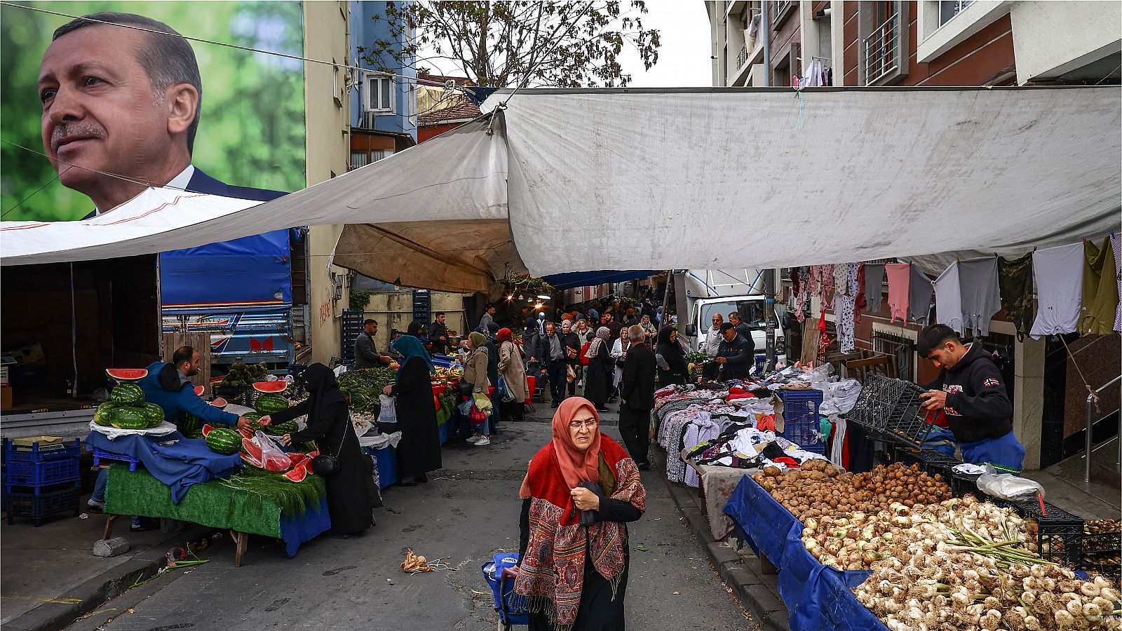Una mujer compra en el mercado local del barrio de Kasimpasa con una foto del presidente turco Recep Tayyip Erdogan al fondo en Estambul