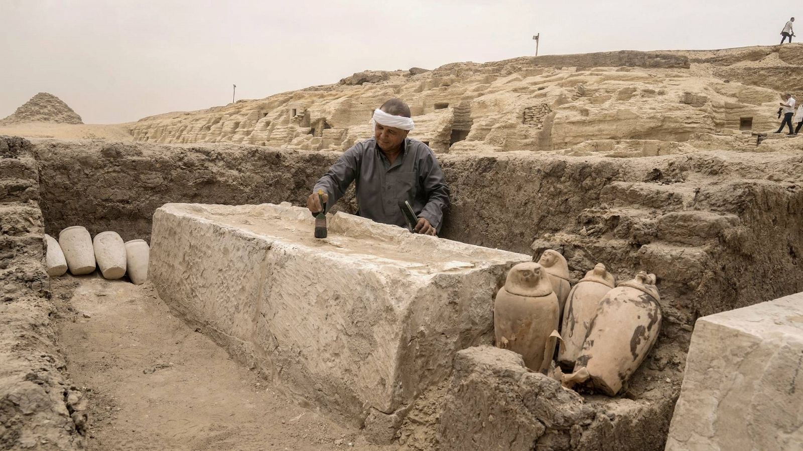 Un hombre cepillando una cama de embalsamamiento en uno de los talleres hallados en Saqqara.