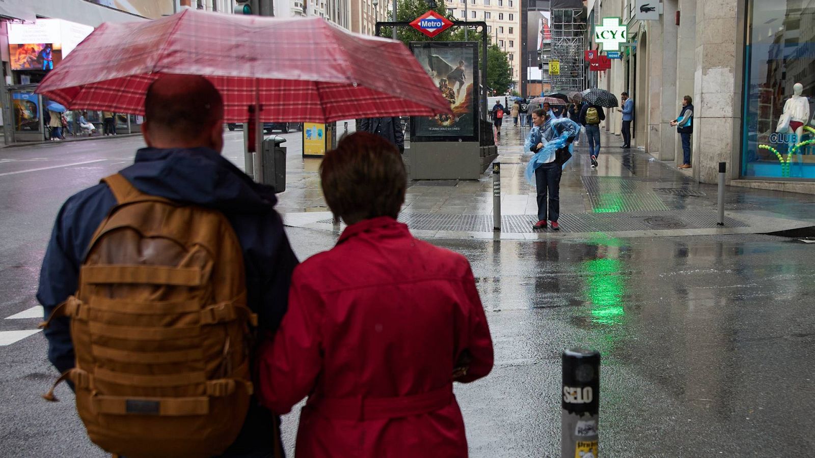 Tiempo hoy: Dos personas con paraguas caminan bajo la lluvia por el centro de Madrid
