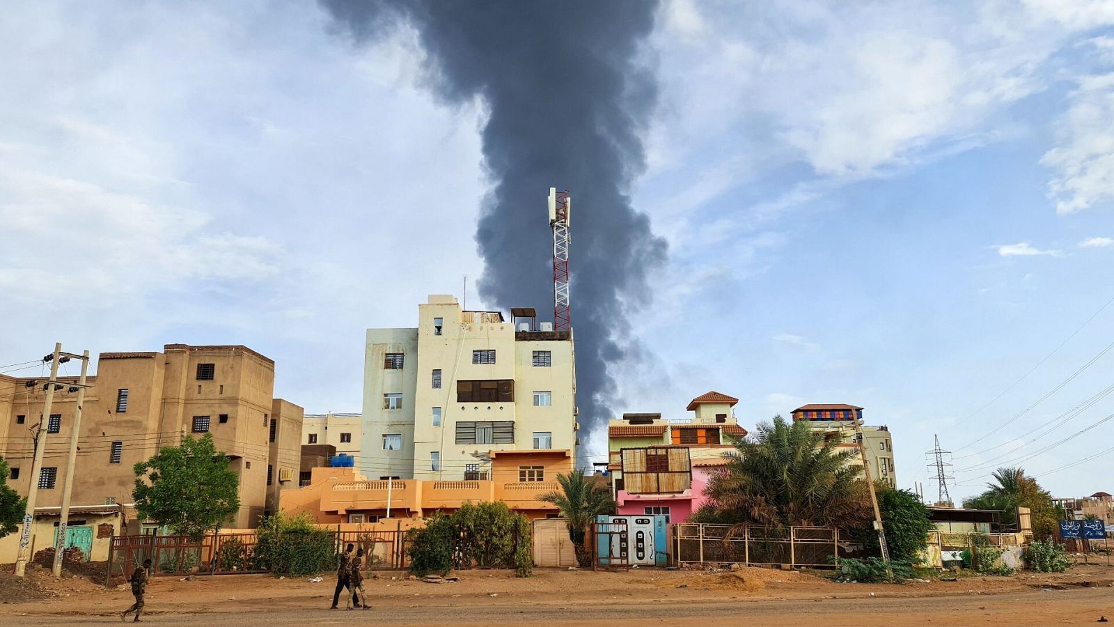 Una columna de humo negro se eleva detrás de los edificios en medio de los combates en Jartum