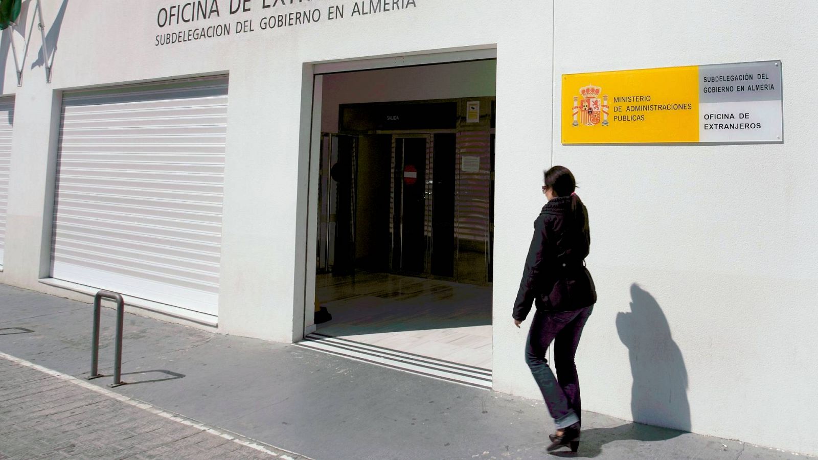Una mujer pasea por la fachada de la oficina de extranjeria en Almería
