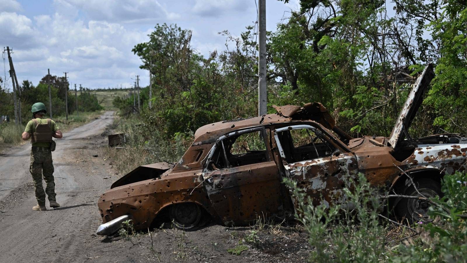 Un militar junto a un coche quemado en Donetsk