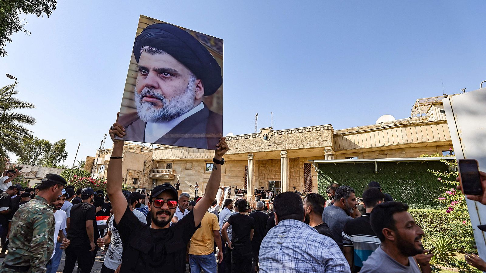 Un simpatizante de Moqtada Sadr levanta una foto del líder musulmán chiíta, mientras otros se manifiestan en el patio de la embajada sueca en Bagdad tras haber irrumpido brevemente en el edificio