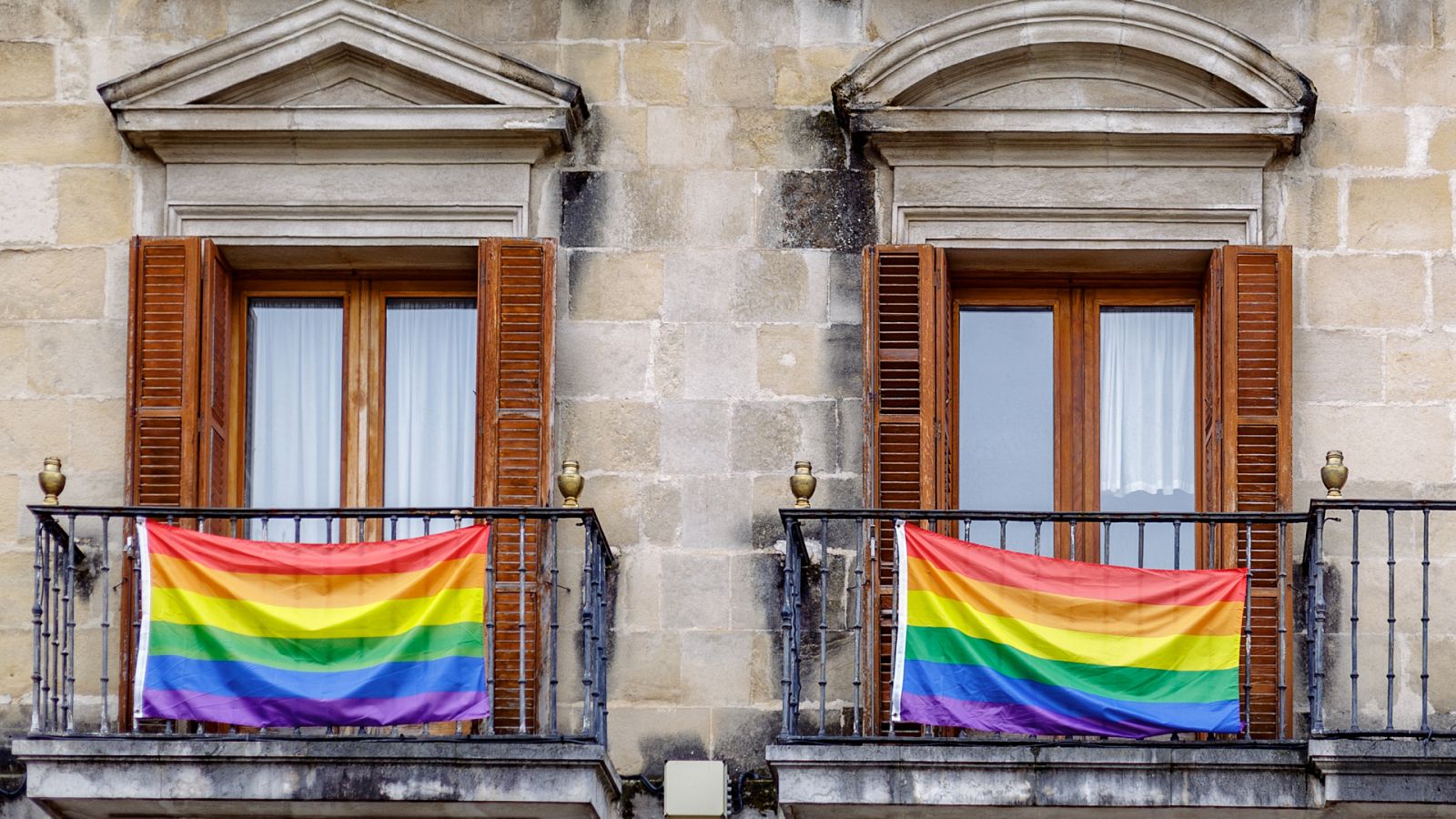 La Justicia de Castilla y León rechaza la retirada urgente de la bandera LGTBI+: banderas LGTBI+ en dos balcones de un edificio