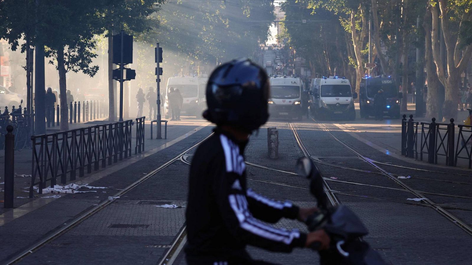 Un hombre en un scooter mira los vehículos de la policía antidisturbios francesa durante una manifestación en Marsella