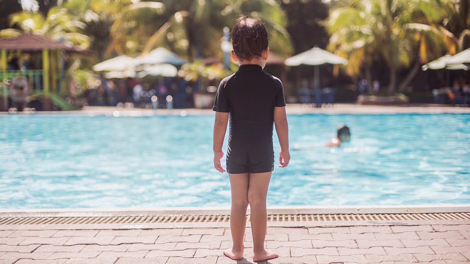 Imagen de archivo de un niño delante de una piscina