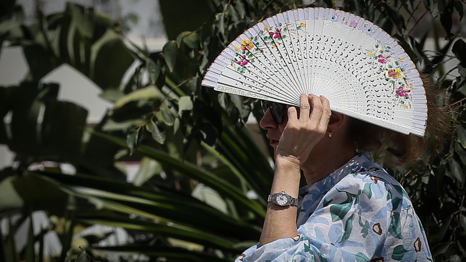 Una mujer se cubre el rostro del sol con un abanico en Sevilla