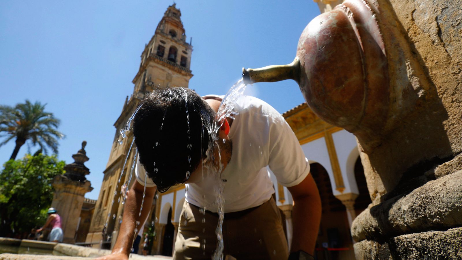 Un turista se refresca en una de las fuentes del Patio de los Naranjos de Córdoba