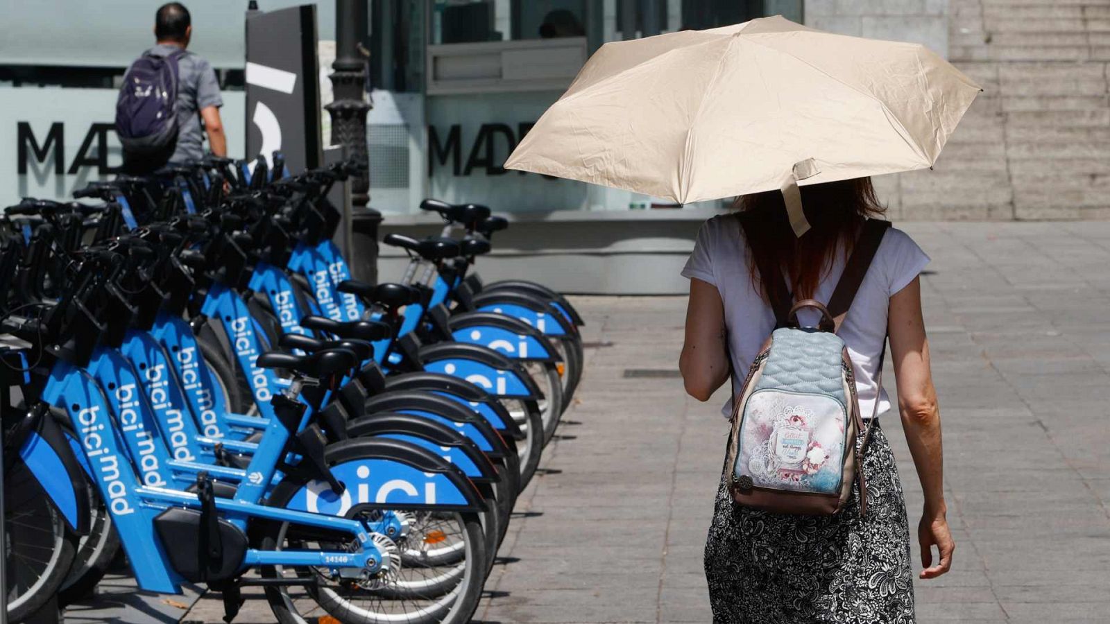 Una mujer se protege del sol con un paraguas mientras camina por el centro de Madrid