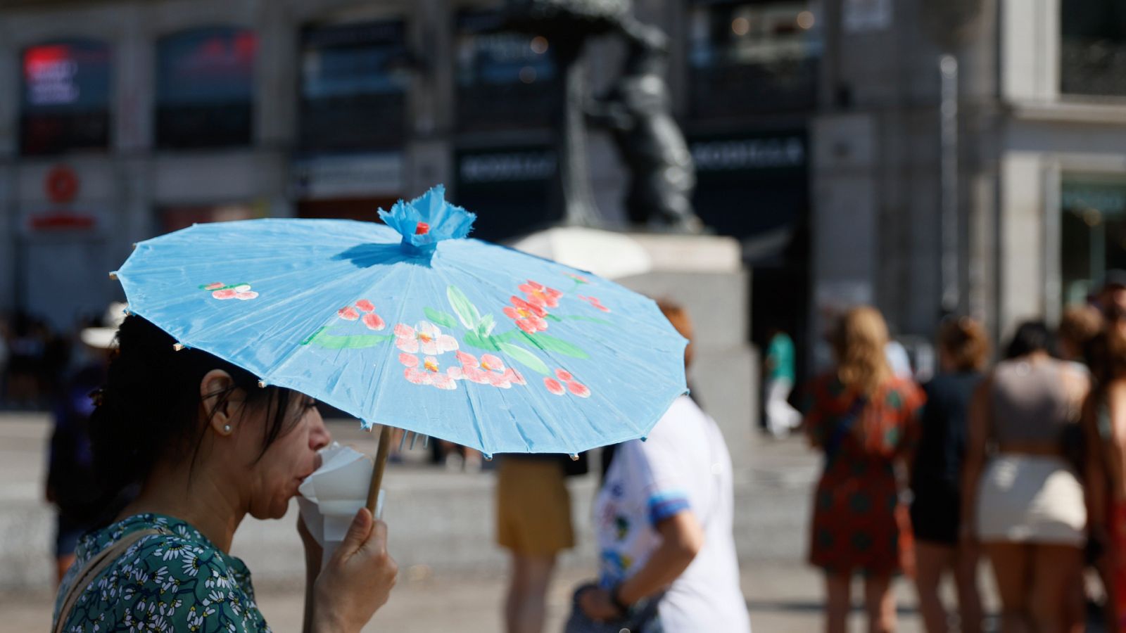 Una joven se protege del sol con una sombrilla en la Puerta del Sol de Madrid.