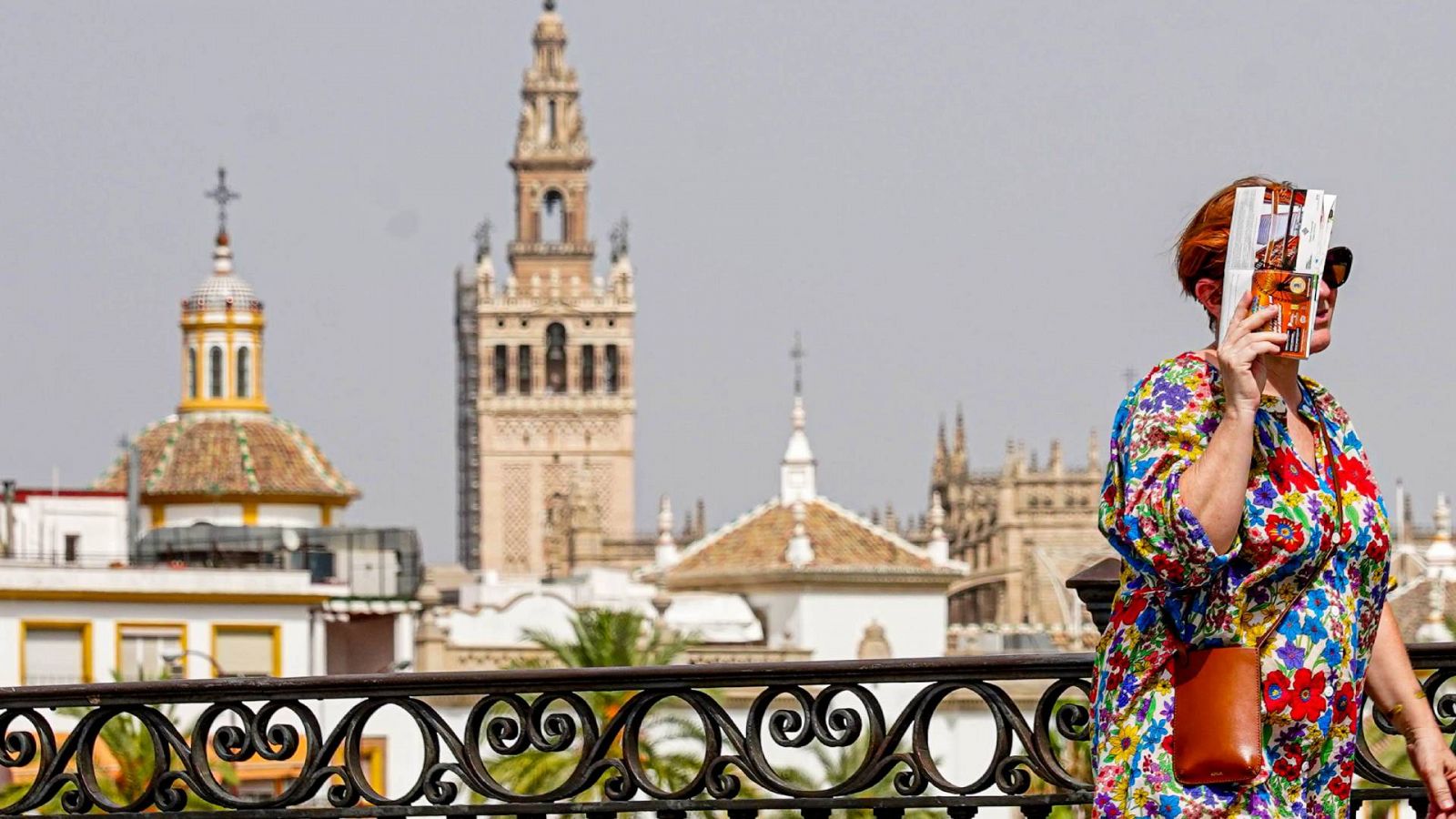 Una mujer pasea por el puente de Triana (Sevilla) mientras se protege del calor