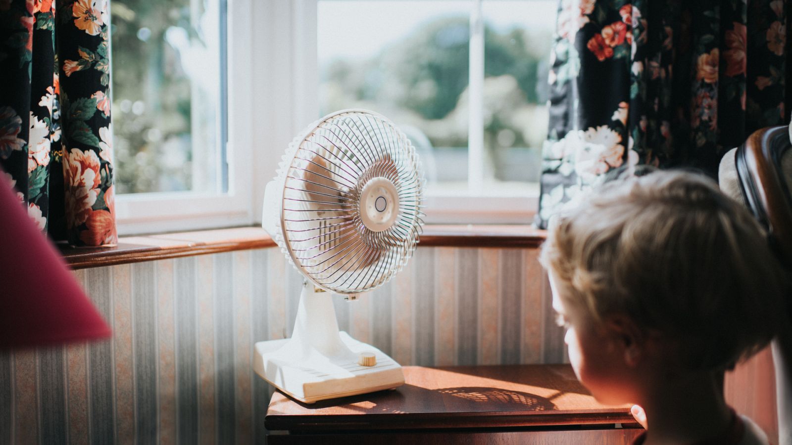 Un niño pasa delante de un ventilador