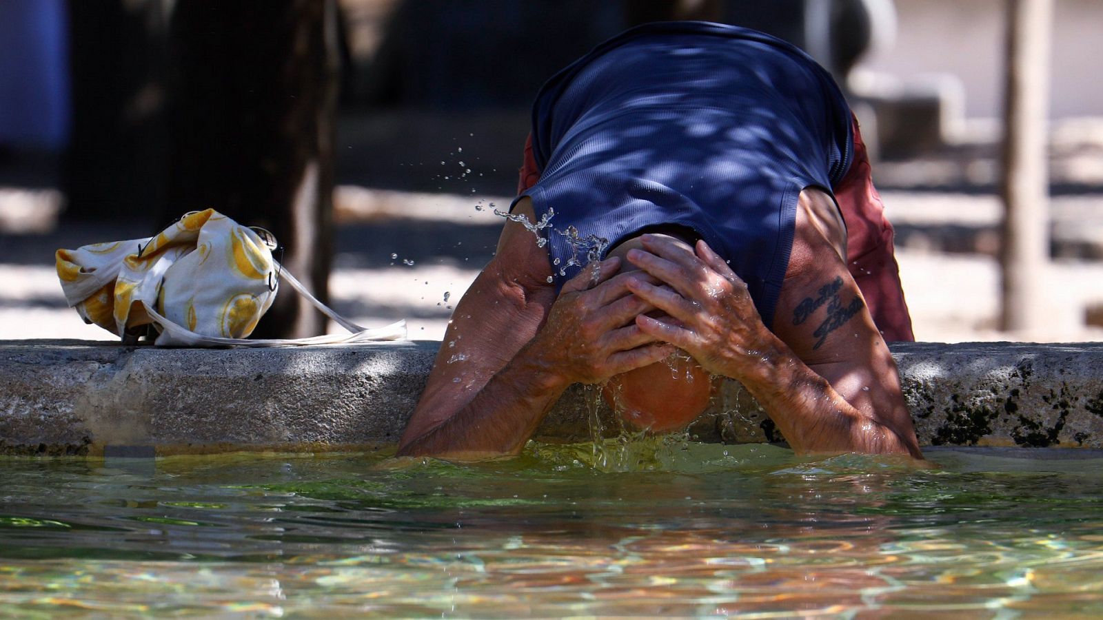 Un turista se refresca este viernes en la Fuente de los Naranjos de la mezquita-catedral de Córdoba