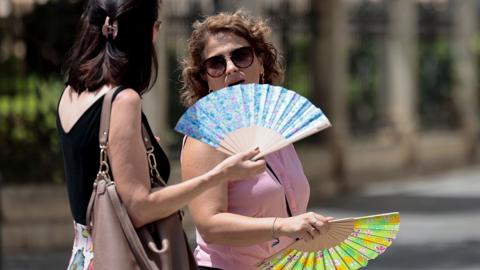 Dos personas combaten las altas temperaturas con abanicos