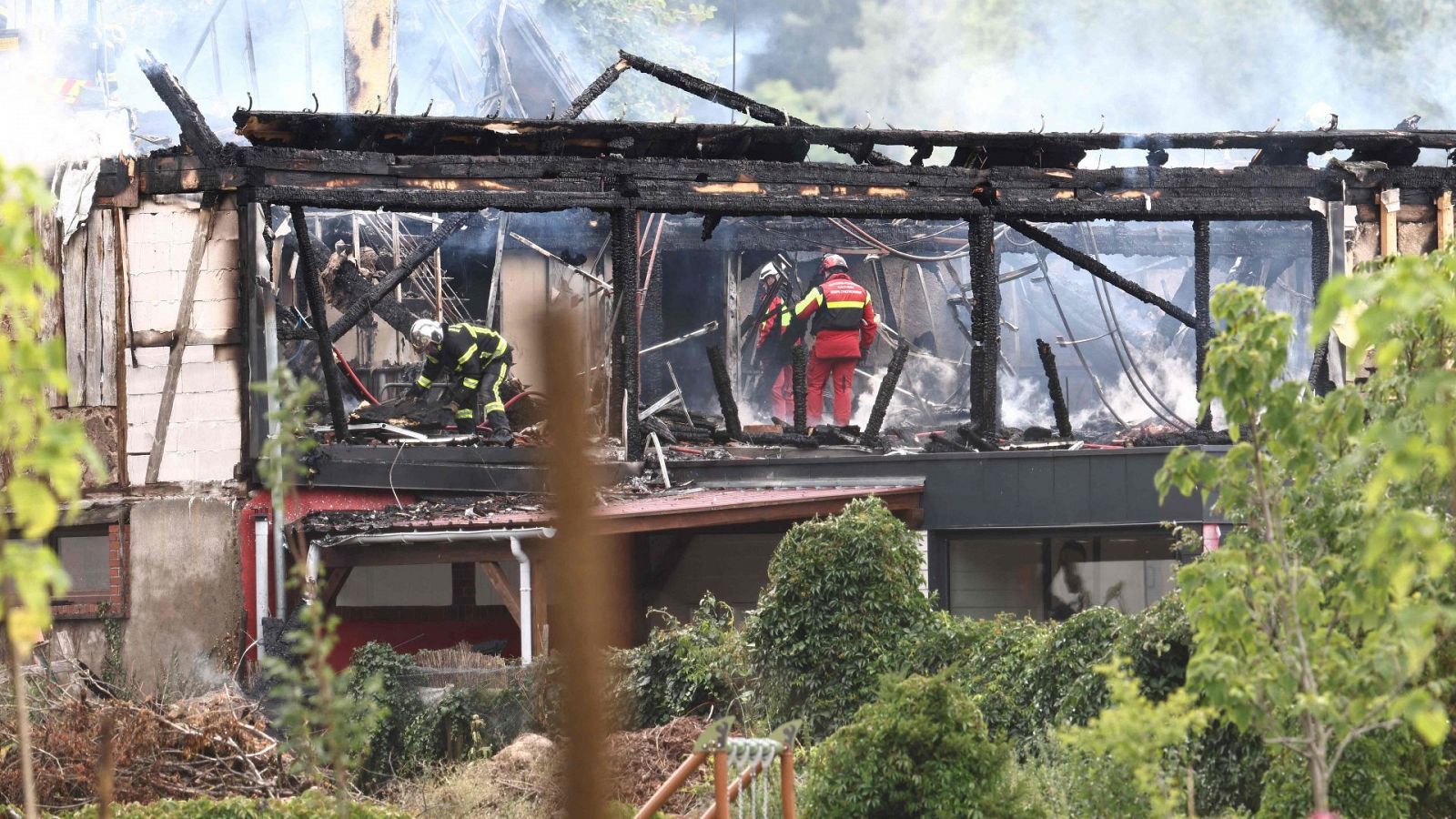 Bomberos trabajan en el albuergue incendiado en Francia , que aparece derruido